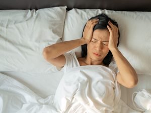 Mulher deitada na cama, exausta, demonstrando como a falta de sono e ansiedade podem afetar negativamente a vida.